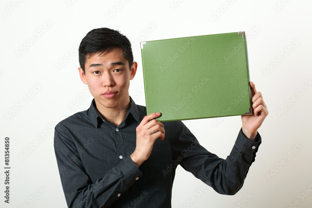 Young Asian man showing green copy space box and looking at came Young Asian man showing green copy space box and looking at came
