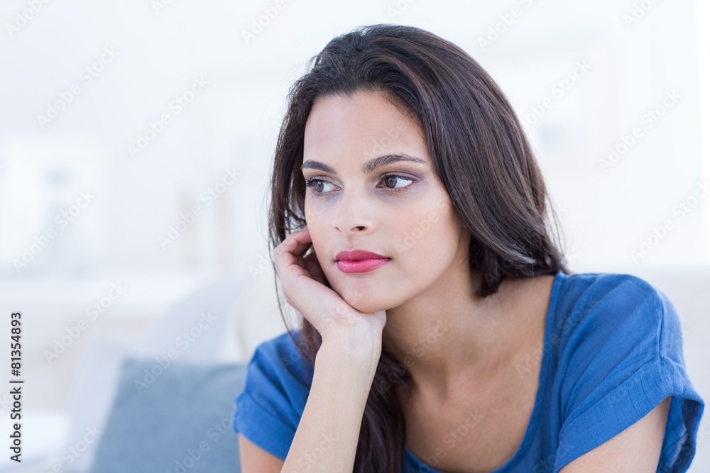 Thoughtful beautiful brunette sitting on the couch Thoughtful beautiful brunette sitting on the couch