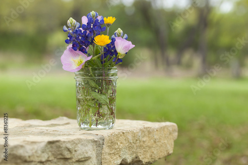 Fototapeta Naklejka Na Ścianę i Meble -  Bouquet of Texas wildflowers in a jar on stone wall
