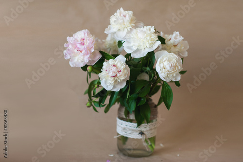 Pink and white bouquet of peonies in a glass vase decorated 