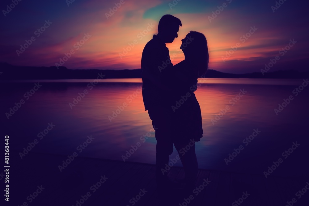 Silhouettes of hugging couple against the sunset sky