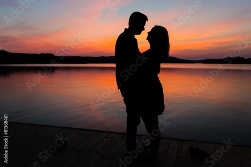 Silhouettes of hugging couple against the sunset sky