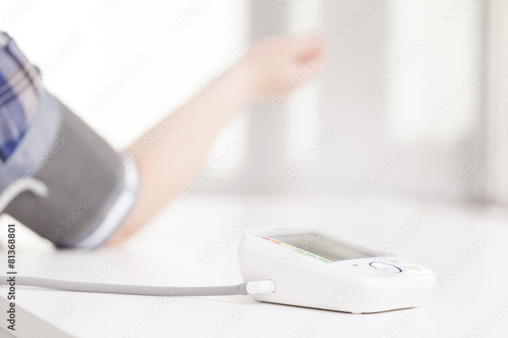 Fototapeta premium Woman measuring blood pressure at doctor's office