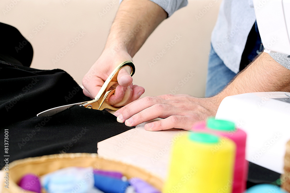 Male dressmaker cut fabric on table close-up