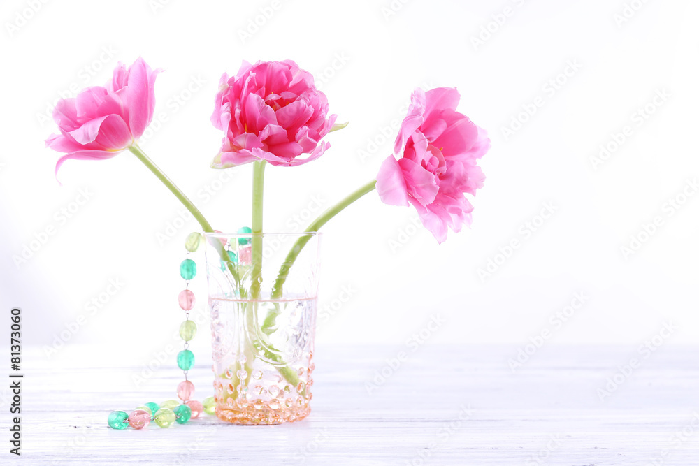 Obraz premium Pink tulips in glass vase with beads isolated on white