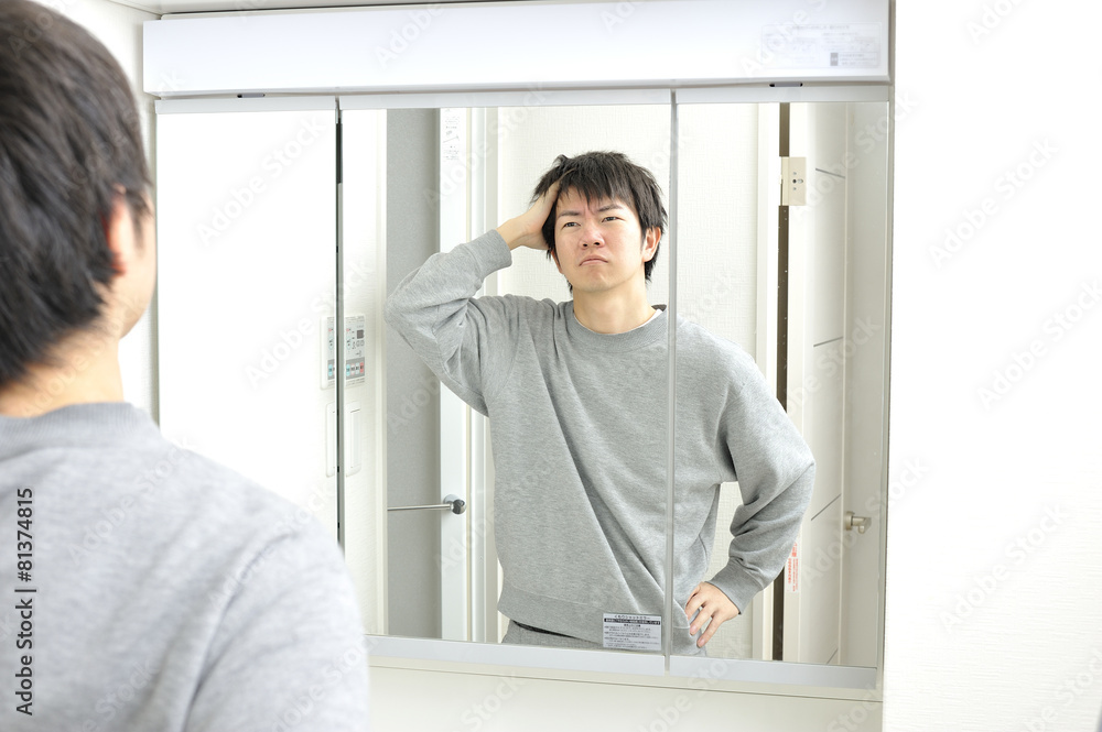 Fototapeta premium 朝起きて自宅の洗面台の鏡に映る眠そうな自分を見つめる日本人男性