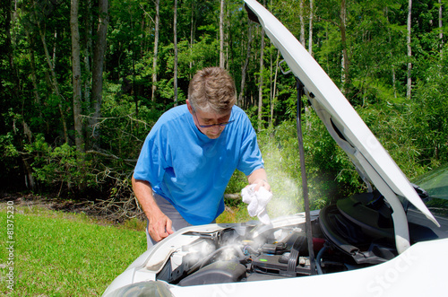 Man in trouble working on overheated smoking broken down car photo