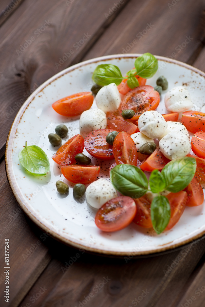 Caprese salad with caper berries, close-up, studio shot Caprese salad with caper berries, close-up, studio shot