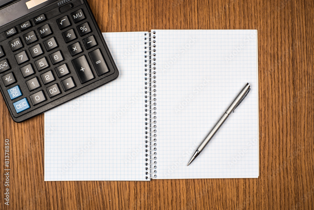 Notebook, ballpen and calculator on wooden desk Notebook, ballpen and calculator on wooden desk