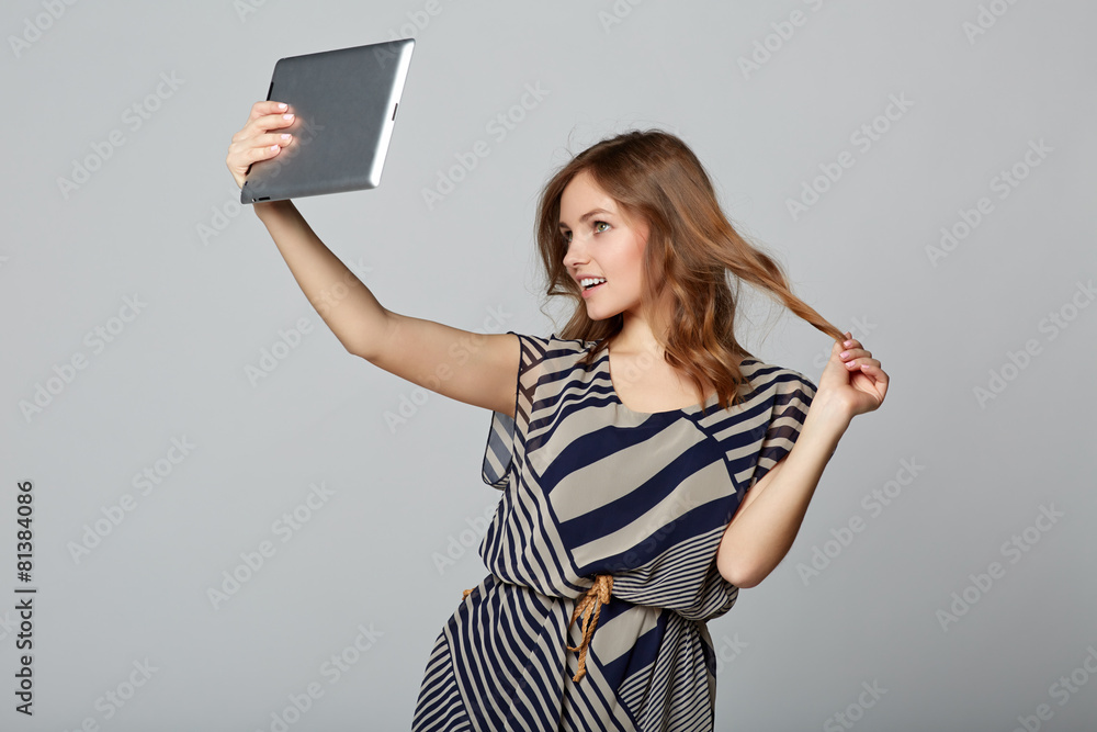 Young woman taking selfie with digital tablet, on gray backgroun Young woman taking selfie with digital tablet, on gray backgroun