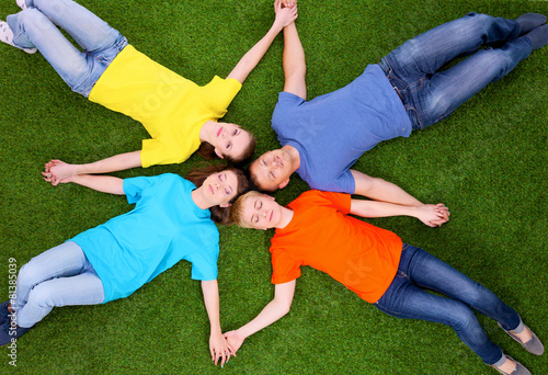 Group of young  people lying on green grass