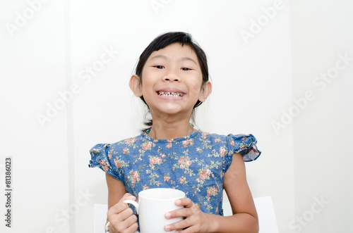 Asian girl holding a cup of milk during breakfast at home. photo