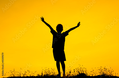 Boy raising his hands standing during sun set