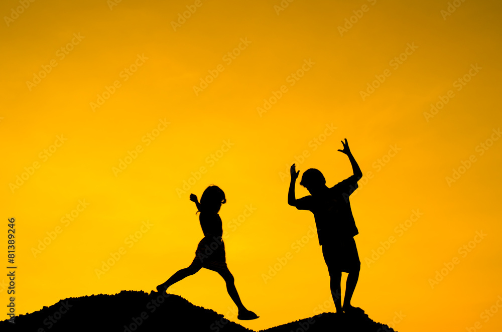 Boy and Girl raising her hands standing on top hill during sun s Boy and Girl raising her hands standing on top hill during sun s