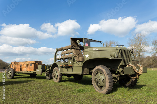 Military jeep pulling trailer carrying wooden boxes with bullets