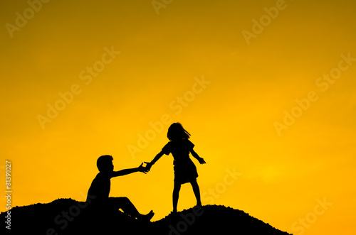 Boy and Girl raising her hands standing on top hill during sun s