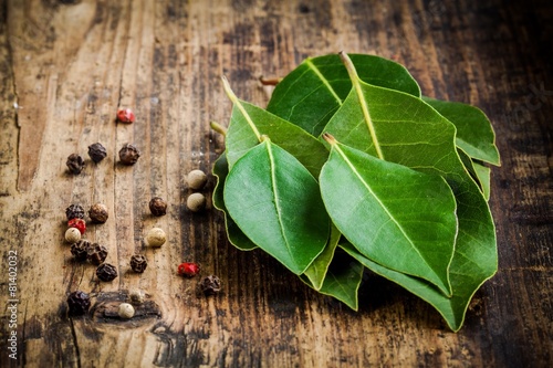 Fresh bay leaves, pepper on a wooden background