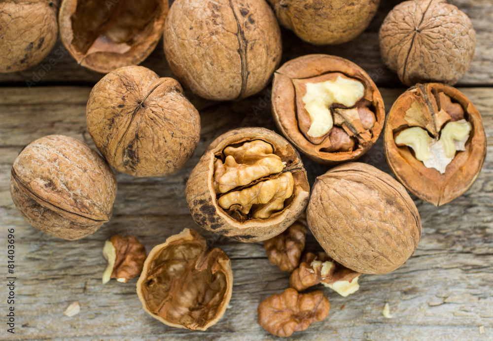 Walnut kernels and whole walnuts on rustic old wooden table Walnut kernels and whole walnuts on rustic old wooden table