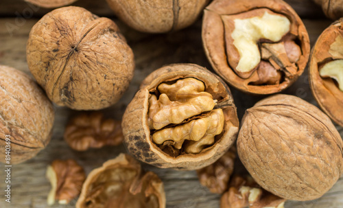 Walnut kernels and whole walnuts on rustic old wooden table