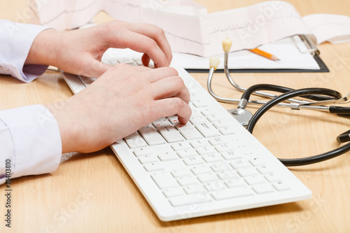 cardiologist works on white PC keyboard