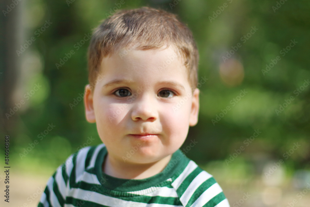 Happy little handsome boy looks at camera in park. Shallow dof Happy little handsome boy looks at camera in park. Shallow dof