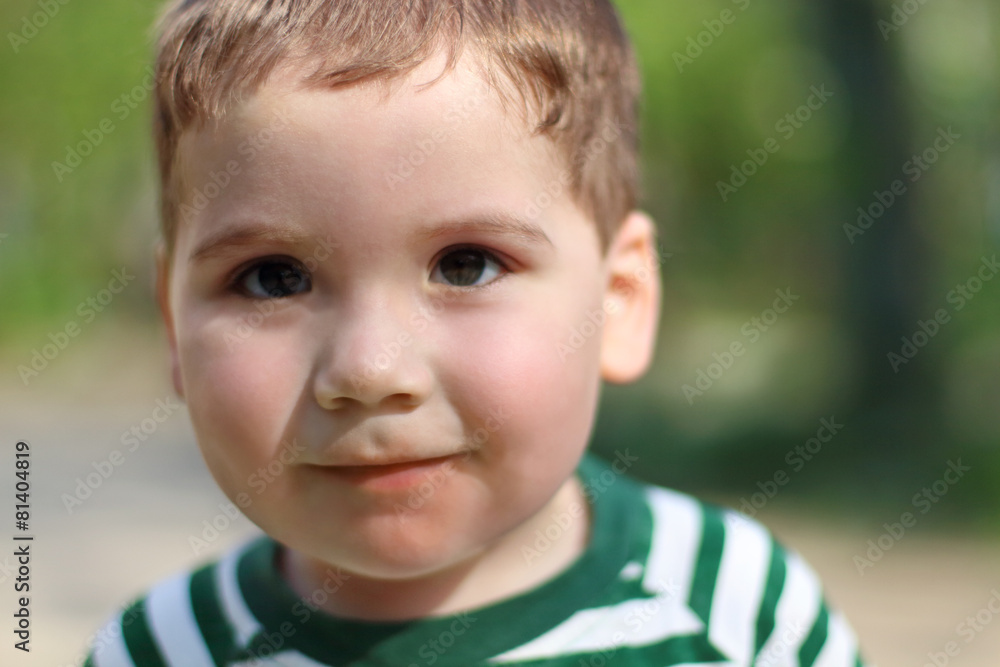 Smiling little cute boy looks at camera in park. Shallow dof Smiling little cute boy looks at camera in park. Shallow dof