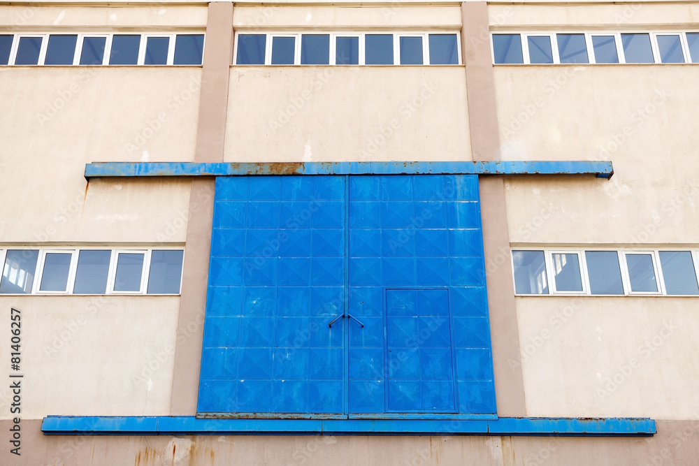 Industrial wall with blue closed metal gate Industrial wall with blue closed metal gate