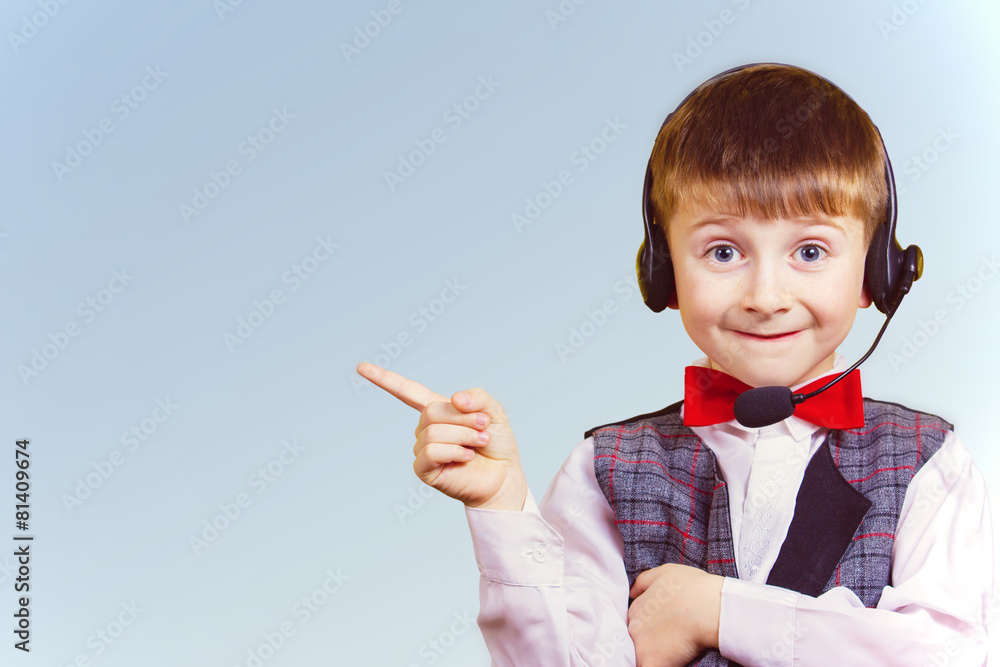 Smiling little boy pointing up with phone headset Smiling little boy pointing up with phone headset