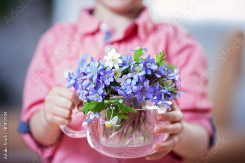 Little hands, holding glass vase with forest spring flower bouqu photo