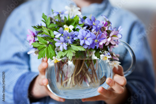 Little hands, holding glass vase with forest spring flower bouqu photo