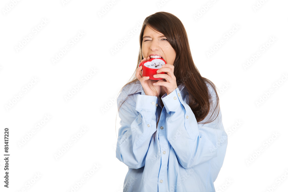 Angry woman in big shirt holding alarm clock. Angry woman in big shirt holding alarm clock.