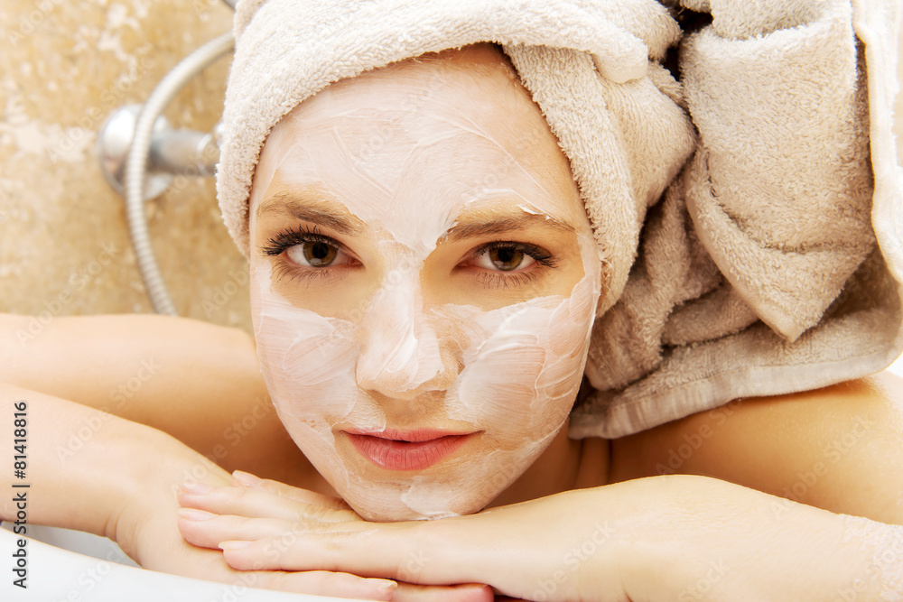 Woman relaxing in bathroom with face mask.