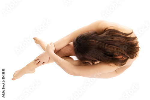 Nude woman curled up on the floor.