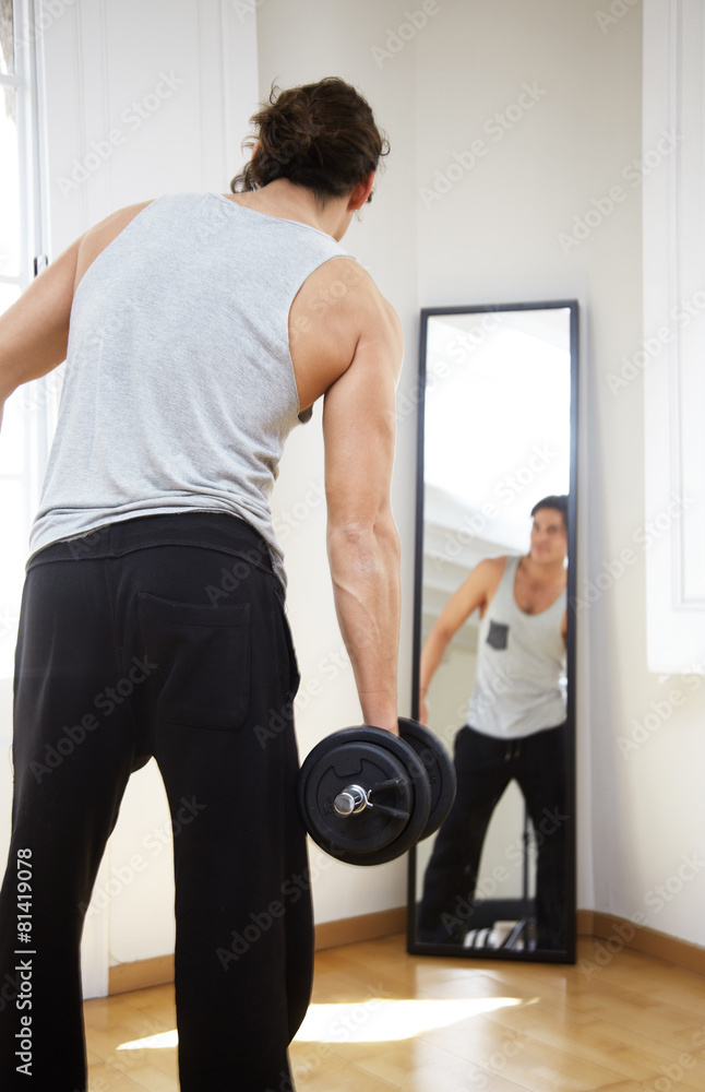 Obraz premium man with a dumbbells in sunny flat with mirror