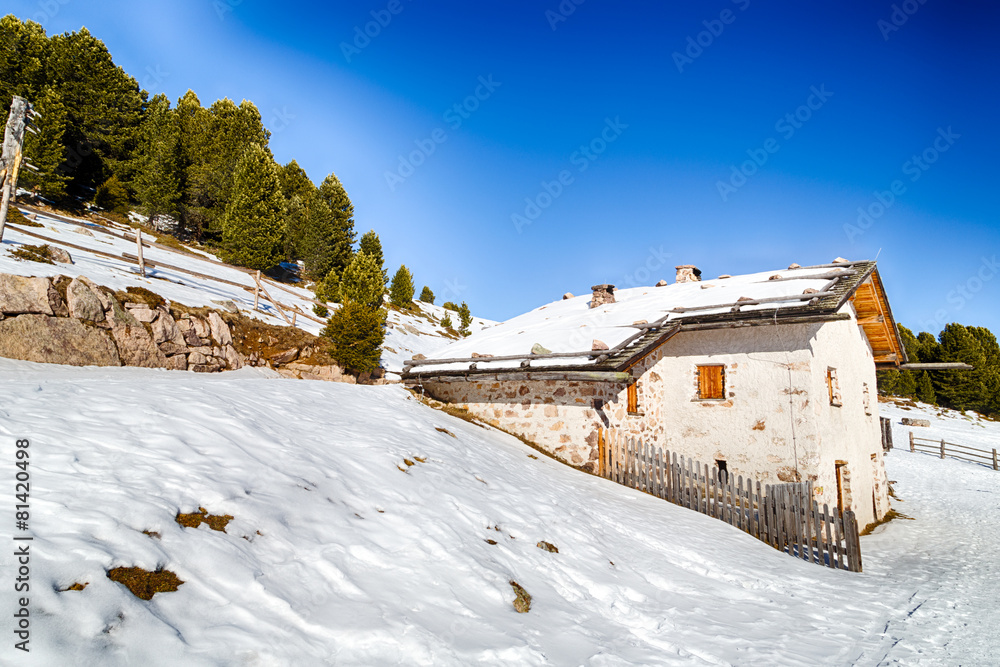 High-altitude mountain hut among snow-capped peaks and pine fore