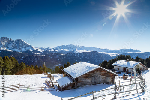 High-altitude mountain hut in front of a panorama of snow-capped