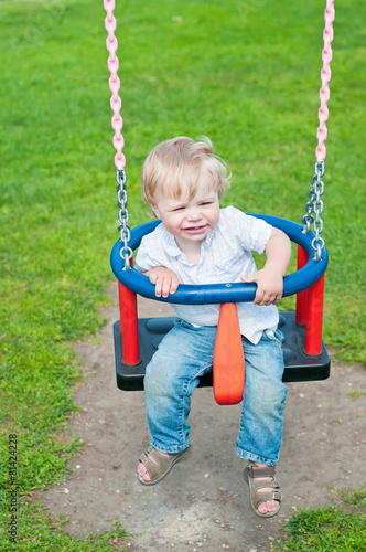 Cute baby boy playing on swing