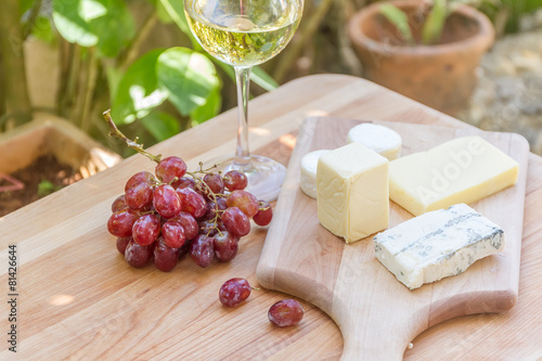 different types of cheese with wine and grapes on natural backgr