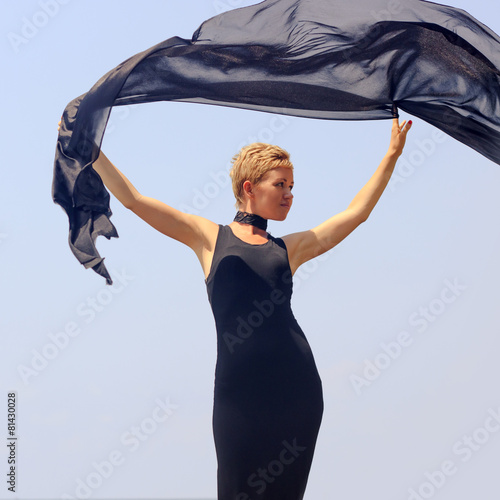 Young woman in black evening dress holding black fabric