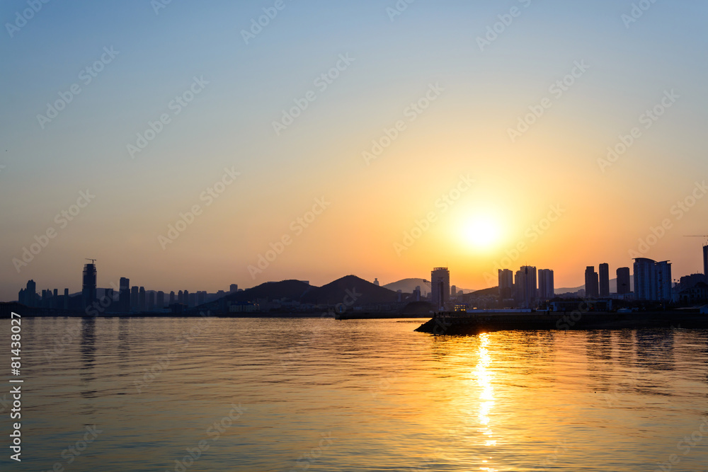 Silhouette of the city with sea at sunset