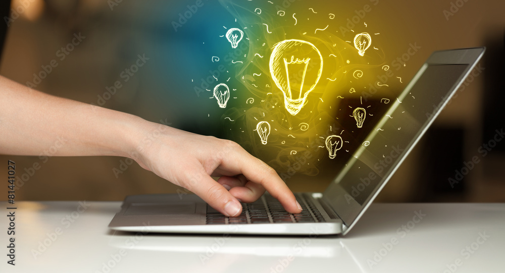 Close up of hand with laptop and idea bulb Close up of hand with laptop and idea bulb