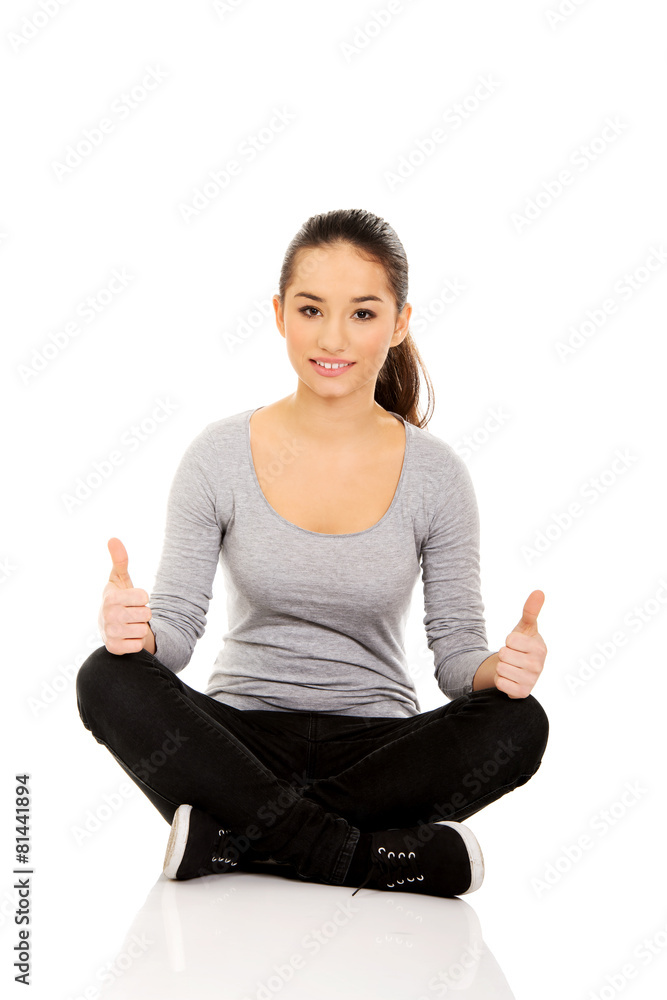 Woman sitting cross legged with thumbs up. Woman sitting cross legged with thumbs up.