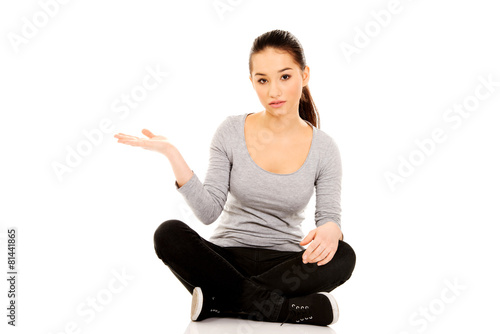 Woman sitting cross legged with open hand. © Piotr Marcinski