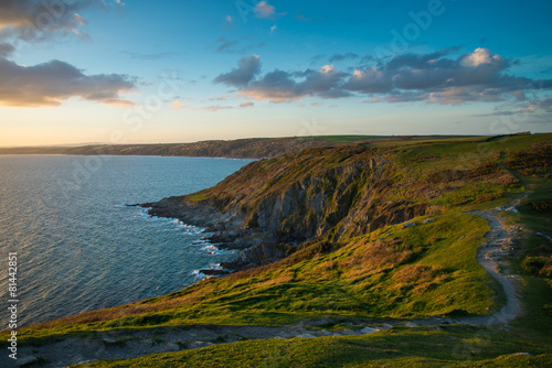 Sunset on Cornish cliffs, ocean and foot patch in wild scenery