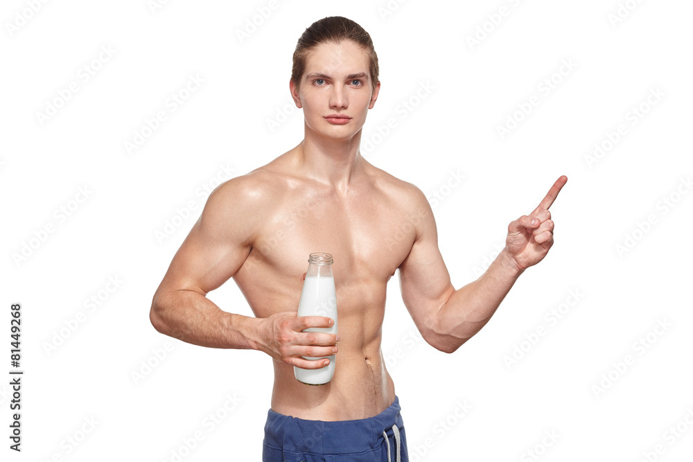 Fototapeta premium Handsome young muscular athlete holding bottle of milk