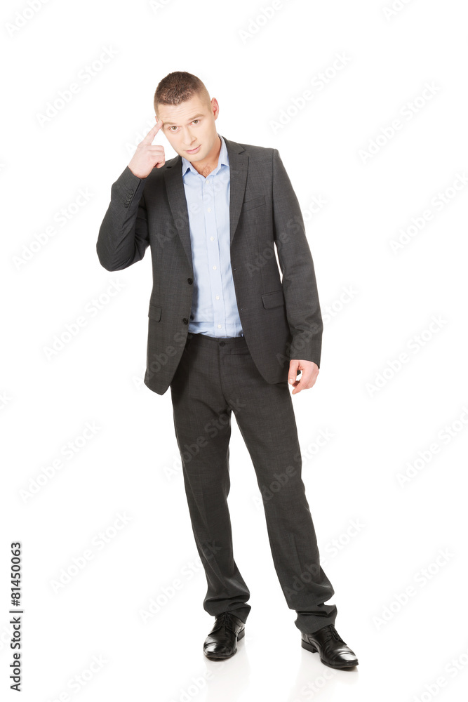 Businessman gesturing with finger against temple Businessman gesturing with finger against temple