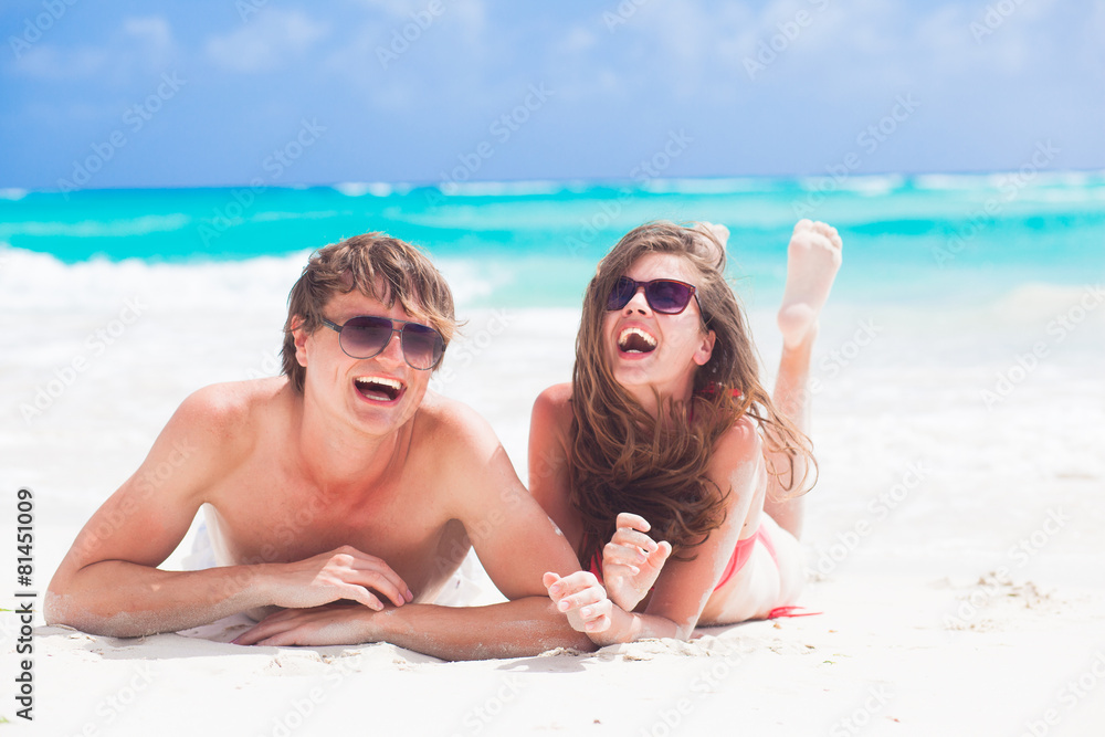 happy young couple lying on a tropical beach in Barbados happy young couple lying on a tropical beach in Barbados