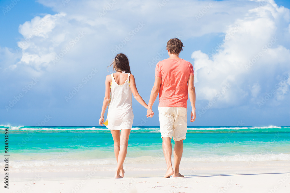 back view of happy romantic young couple on the beach