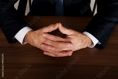 Businessman clenched hands on the desk