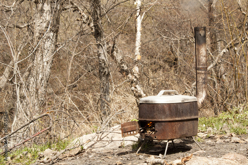 Portable stove in nature with fire inside